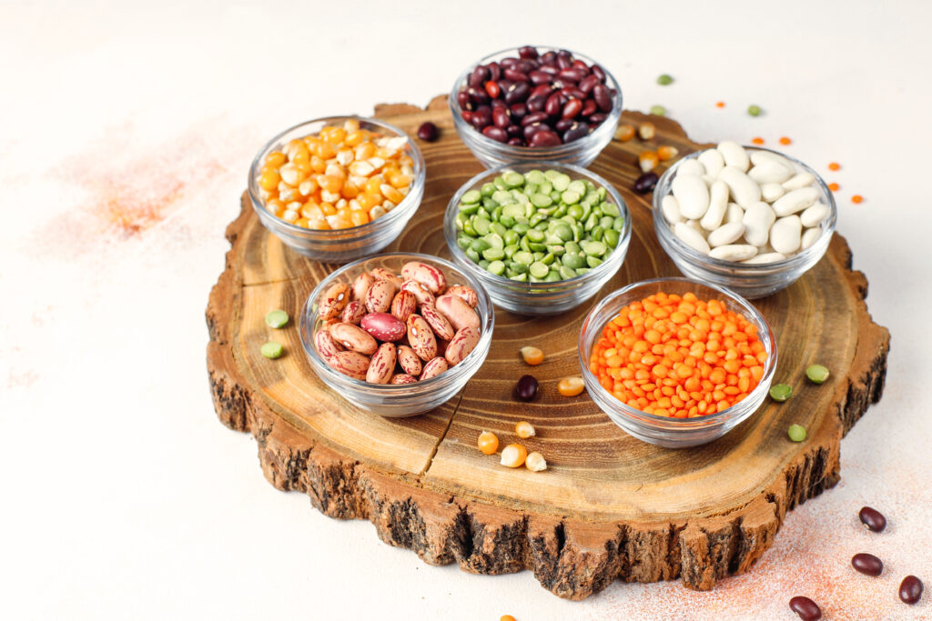 Assorted high protein beans in india displayed in small bowls on a rustic wooden tray 
